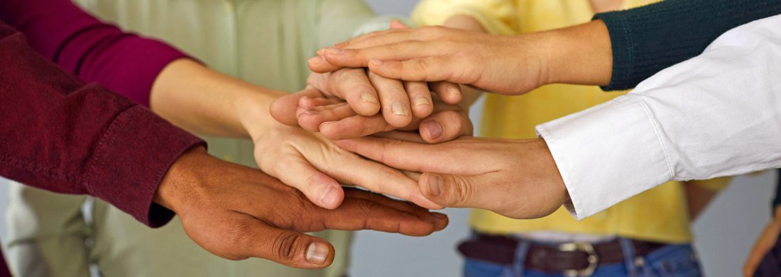 Close up of a group of international people stacking hands and supporting each other