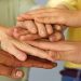 Close up of a group of international people stacking hands and supporting each other