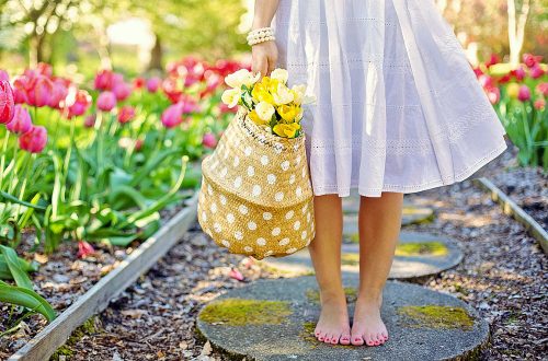 Woman standing on a path next to spring flowers