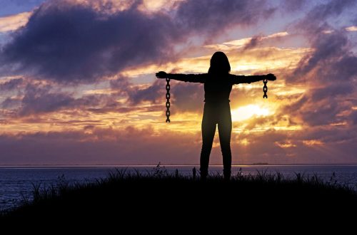 A woman with arms outstretched and broken chains