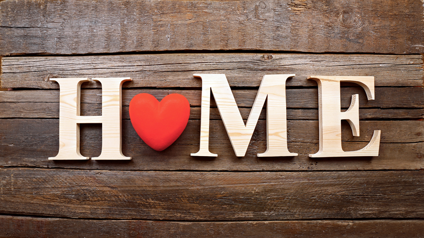 Decorative letters forming word HOME with heart on wooden background