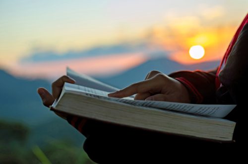 Silhouette of human reading book at sky sunset.