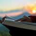 Silhouette of human reading book at sky sunset.