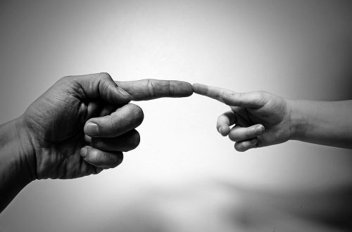 A dad's index finger touches a child's index finger