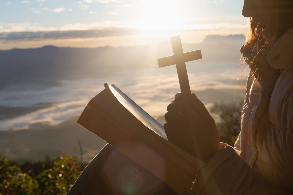 Woman holding a cross and praying to God