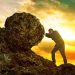 Business man pushing large stone uphill