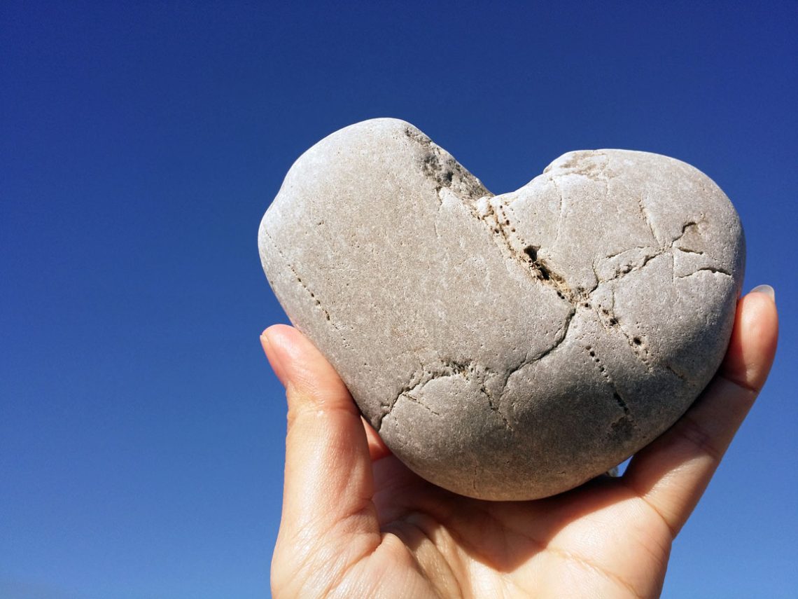 holding heart rock on the blue sky
