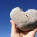 holding heart rock on the blue sky