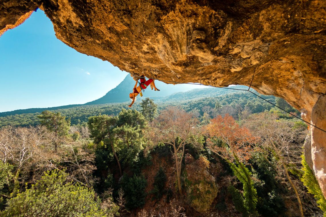 girl rock climber climbs a rock against the backdrop of a forest