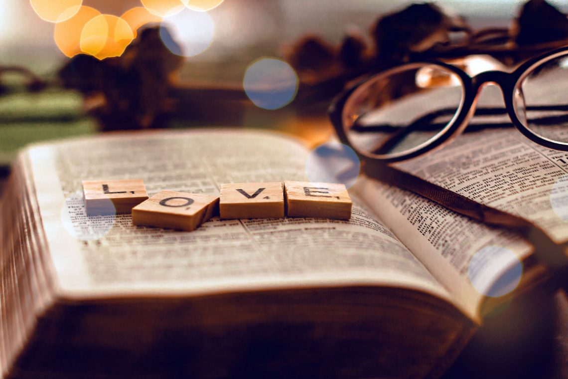 Tile letters spell love on top of a Bible