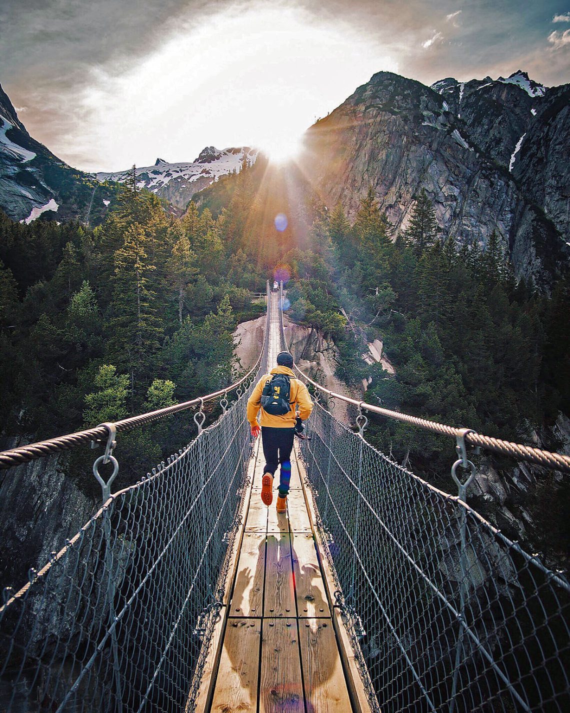 A runner crossing a bridge between mountains