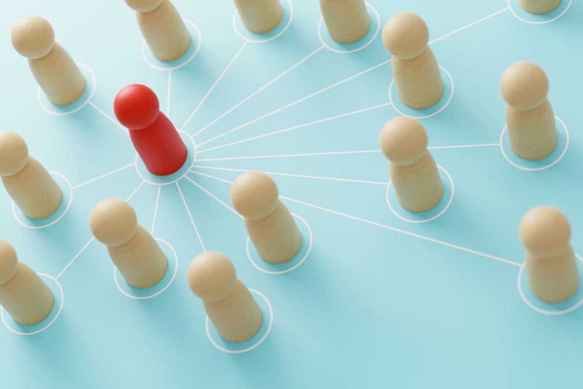 One red peg is connected to other wooden, natural-colored pegs signifying infuence