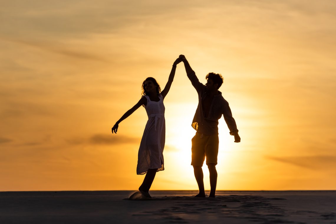 Silhouettes of man and woman dancing on beach