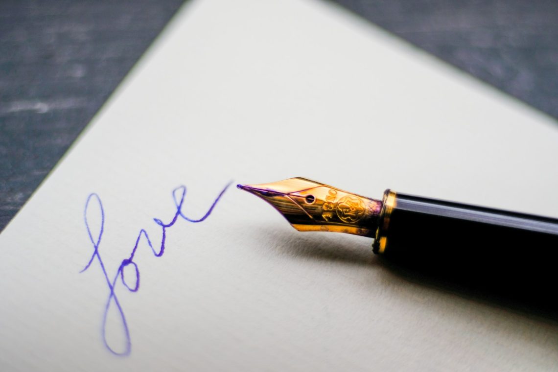 A fountain pen and the word "love" written on a page