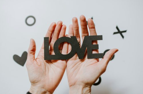 Two hands holding letter cut-outs spelling "love"