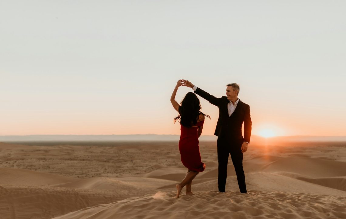 A couple dancing on sand at sunset