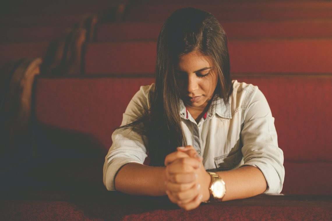 A woman who is kneeling and praying