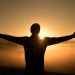 Man with arms outstretched in front of a sunrise