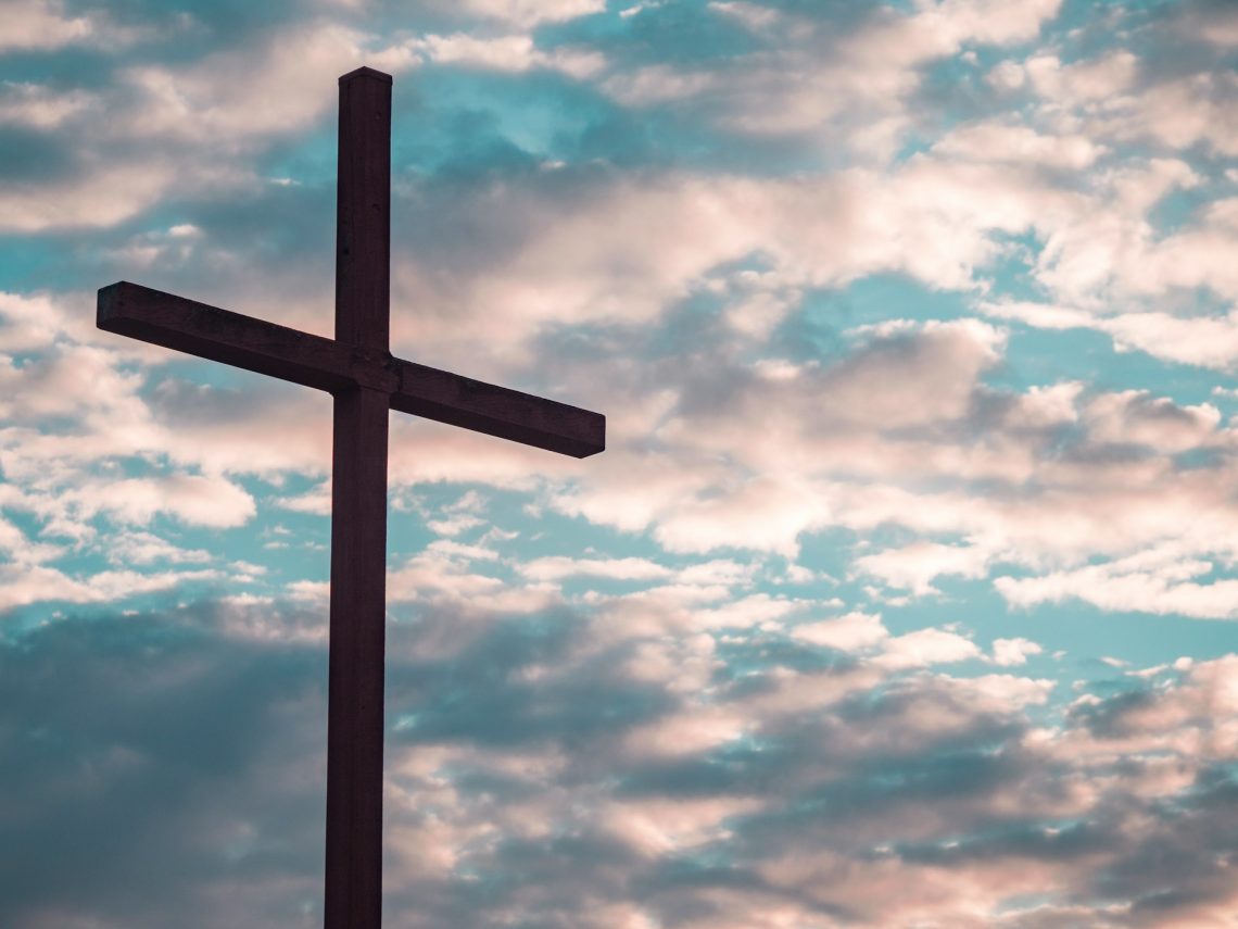 Cross in front of gray and white clouds