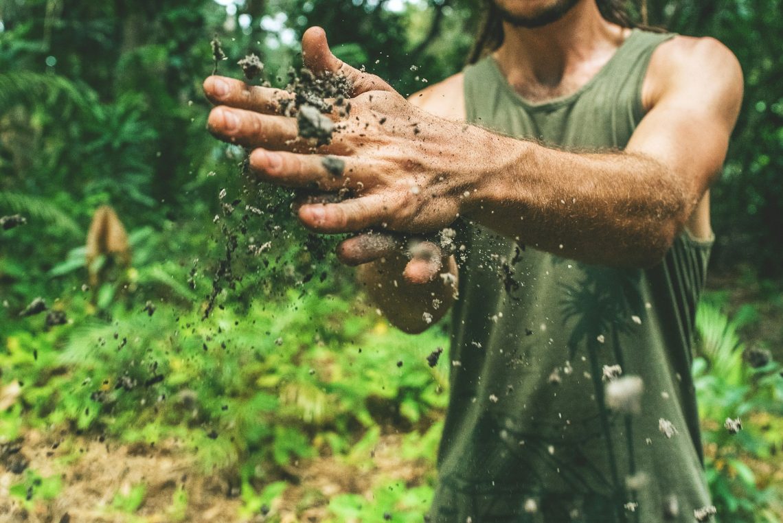 Man sifting through dirt in a forest