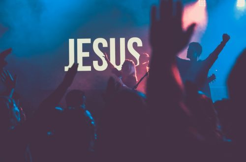 A crowd worshiping Jesus with His name on the wall
