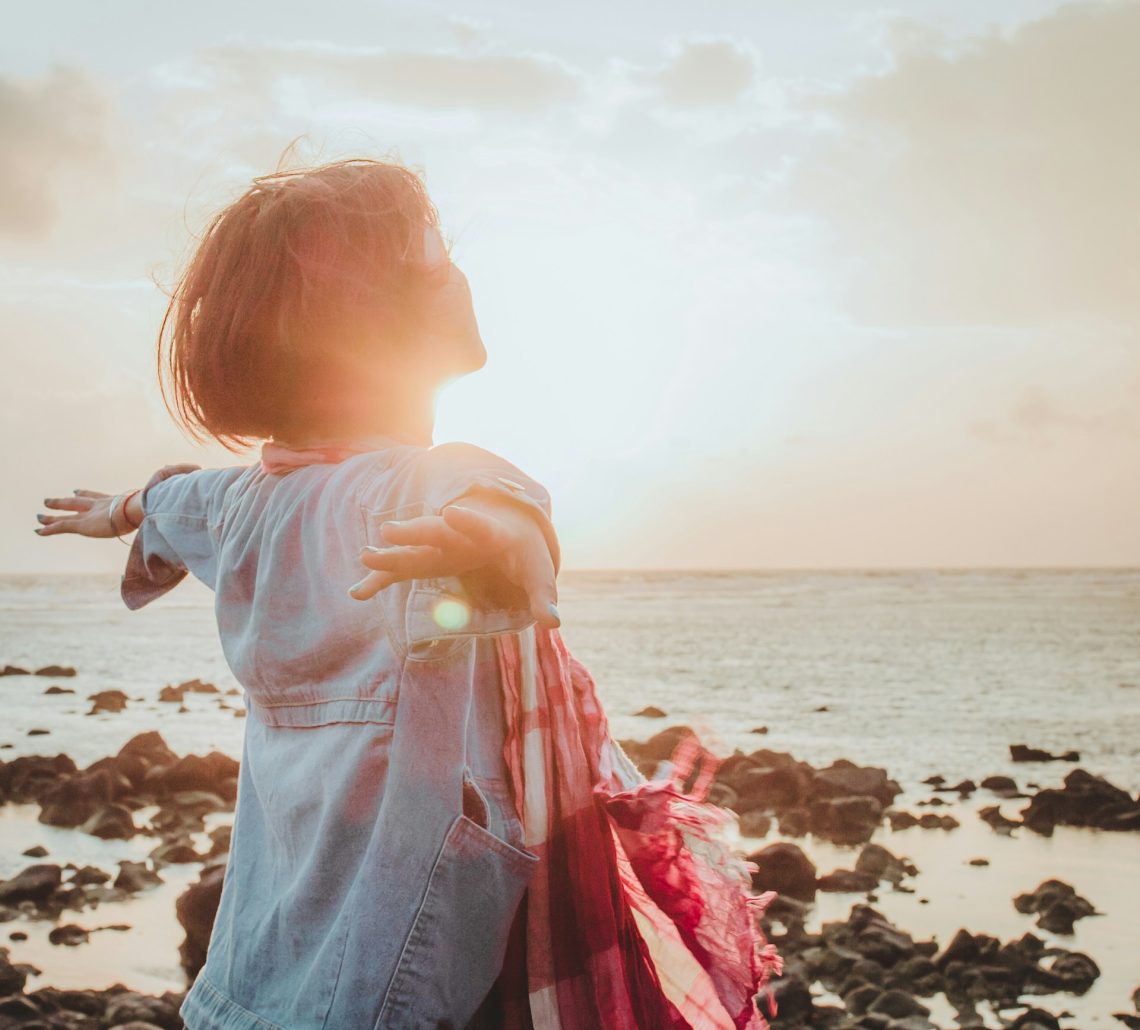 A woman with arms outstretched by the sea