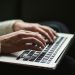 A writer typing on a keyboard