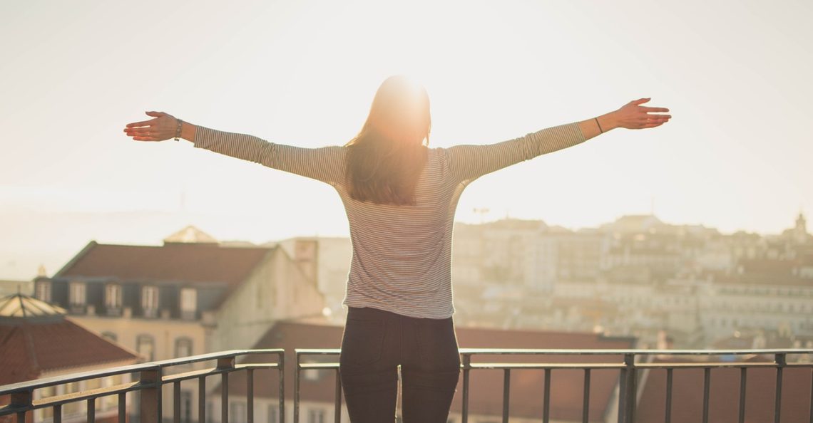 Woman standing on balcony with arms outstretched
