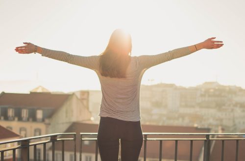 Woman standing on balcony with arms outstretched