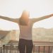 Woman standing on balcony with arms outstretched