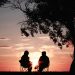 Two people sitting and talking in front of a sunset