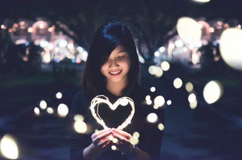 A young woman holding a heart made out of a light "rope"