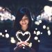 A young woman holding a heart made out of a light "rope"