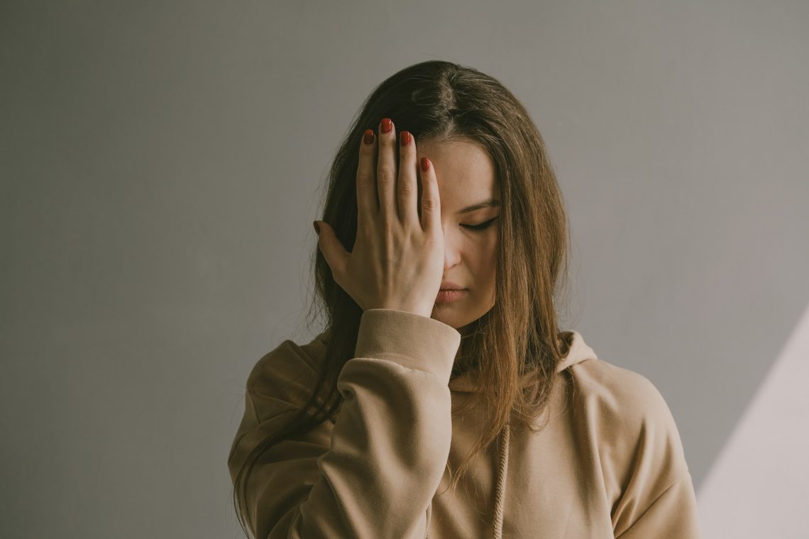 A woman holding her hand against her face in emotional pain