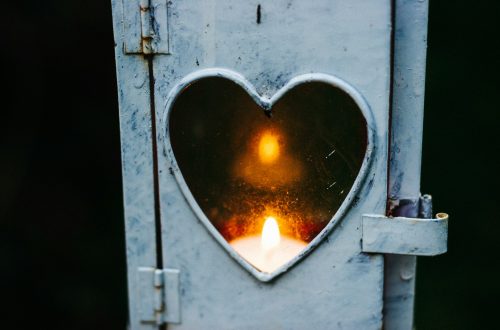 A candle burning in a lantern with a heart window