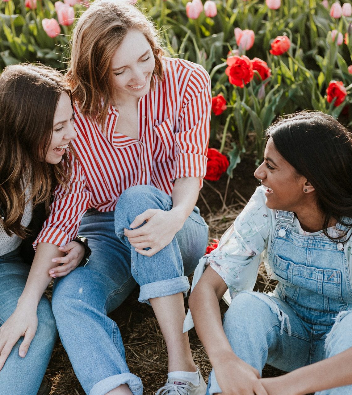3 women talking and laughing in a field of flowers