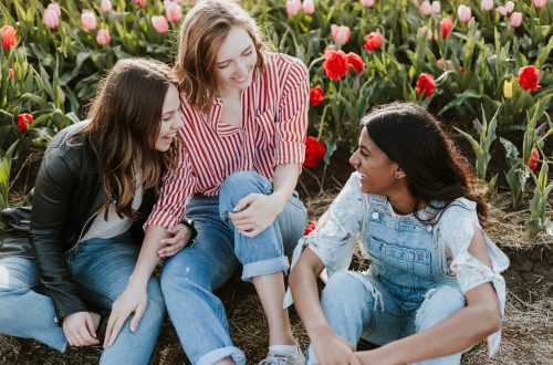3 women talking and laughing in a field of flowers