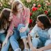 3 women talking and laughing in a field of flowers