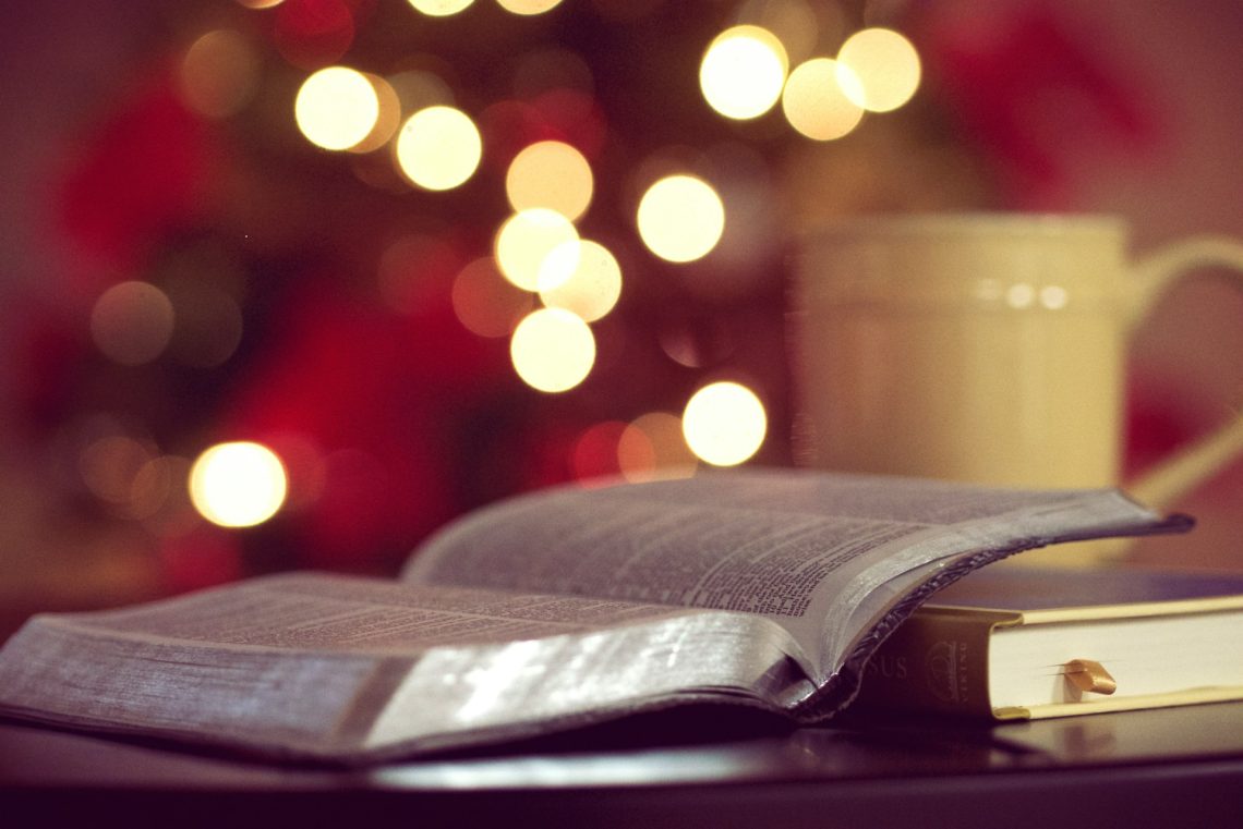 Bible and mug in front of Christmas lights