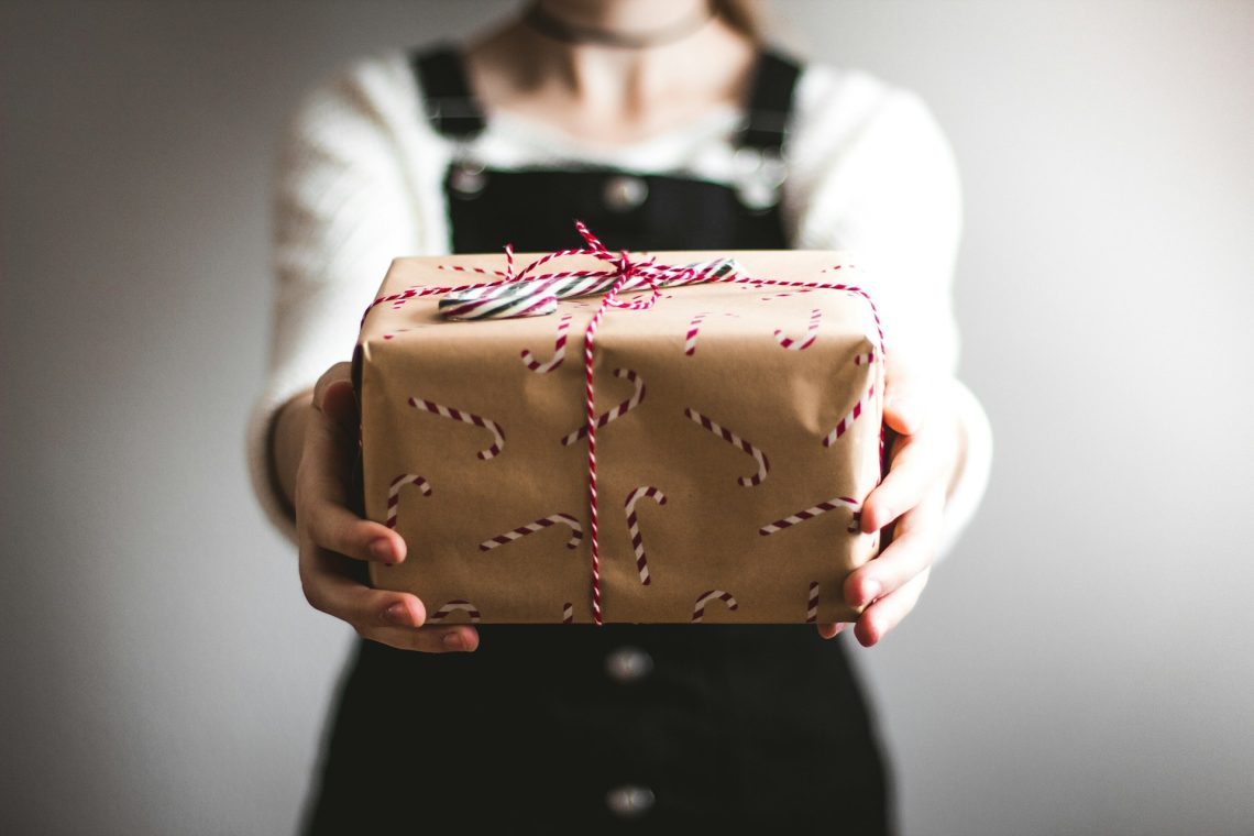A woman holding out a Christmas present