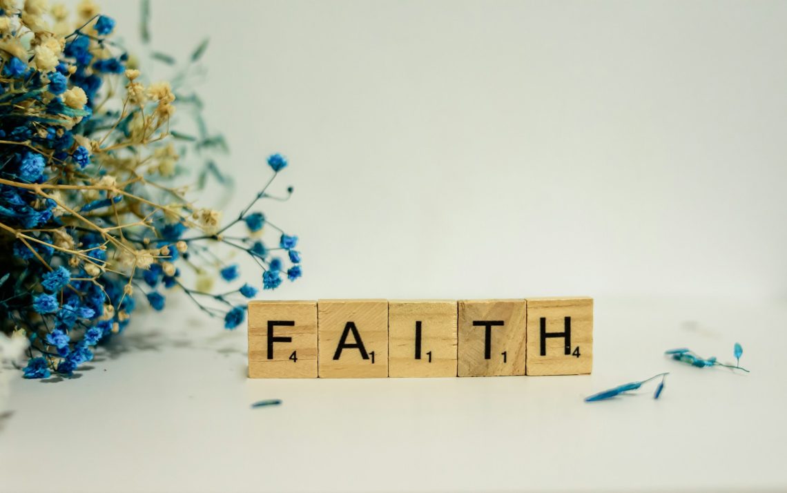 "Faith" spelled on letter tiles next to a dried-flower bouquet
