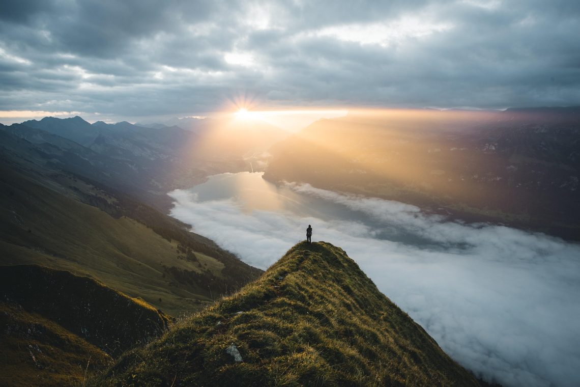 A person standing on a mountaintop watching the sunrise