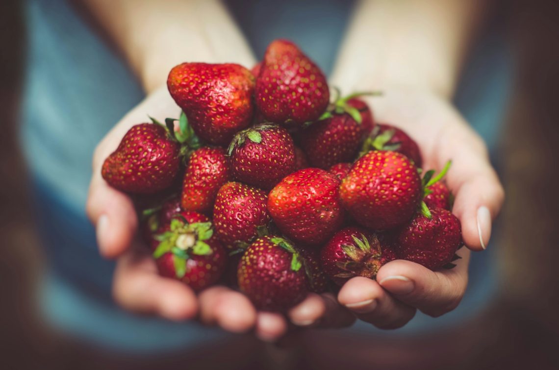 Two hands holding strawberries