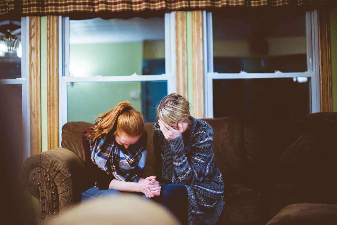 Two women with heads bowed and praying