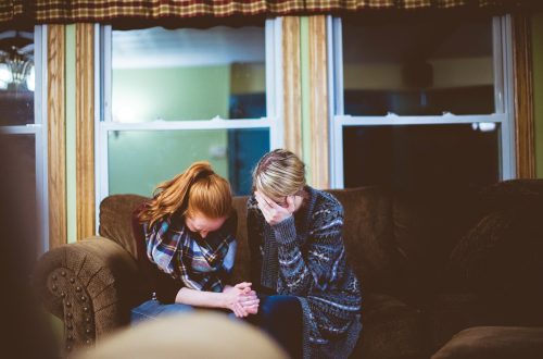 Two women with heads bowed and praying