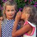 A little girl sharing a secret with another little girl