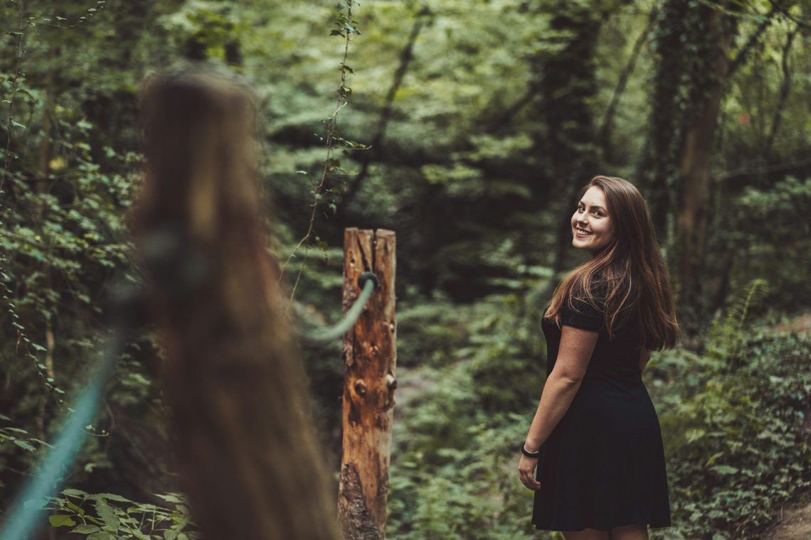 A young woman looks over her shoulder as she walks though the woods