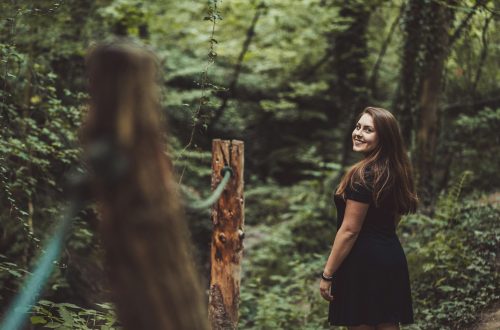 A young woman looks over her shoulder as she walks though the woods