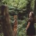 A young woman looks over her shoulder as she walks though the woods