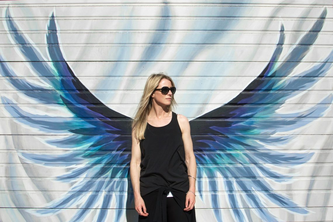 A woman standing in front of wings painted on a wall